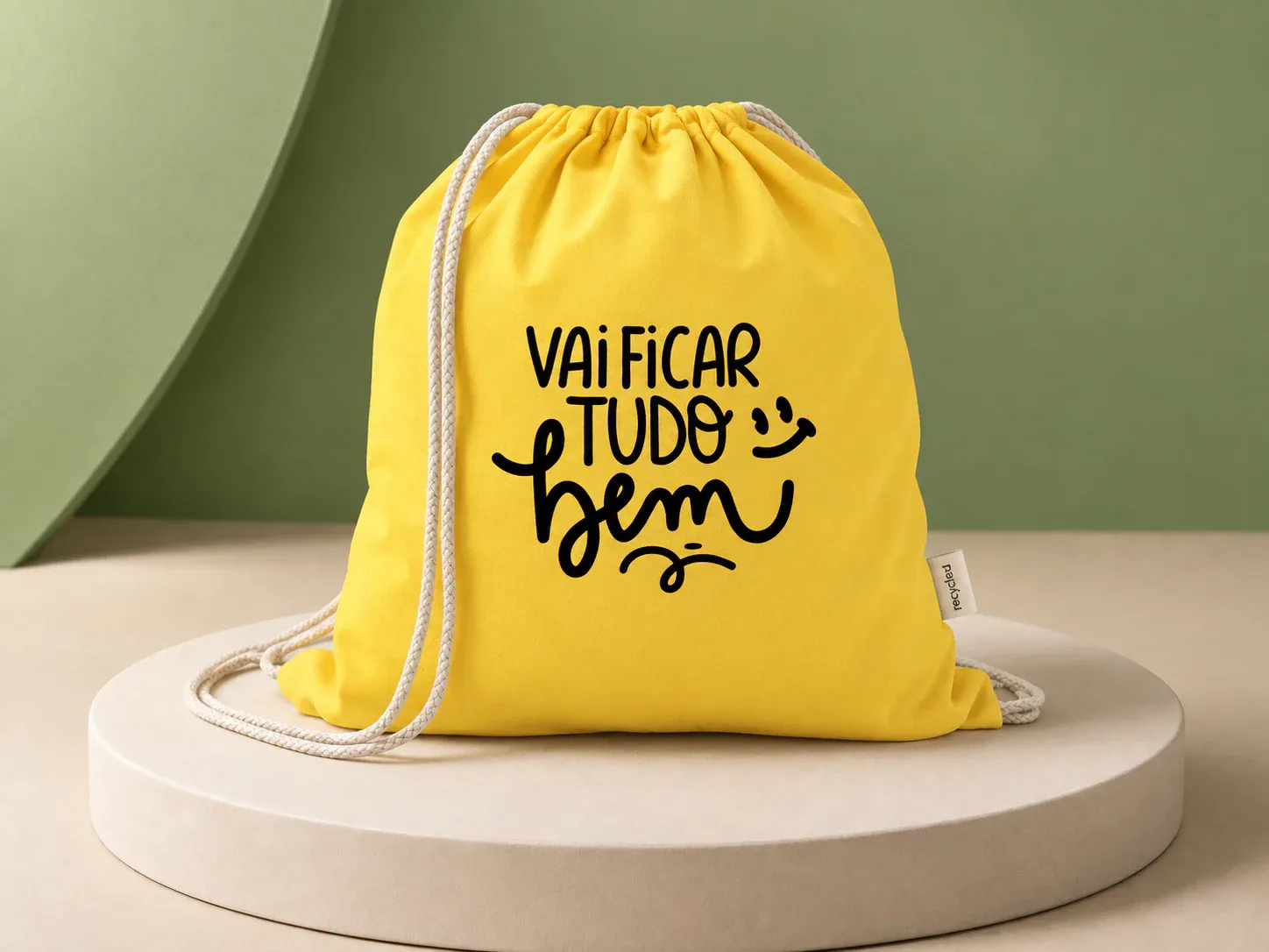 Mochila saco Setembro Amarelo, na cor amarelo, com a arte da campanha e sem a sua marca: mochila saco amarela com cordões claros e a frase "Vai ficar tudo bem" impressa em preto