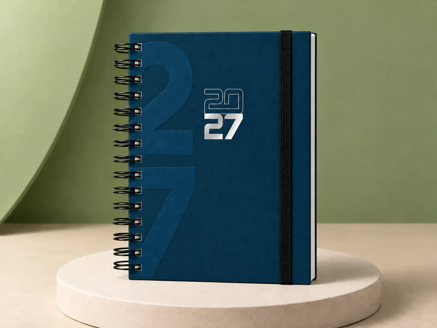 Agenda azul-petróleo com espiral e elástico, na cor azul-petróleo, sem personalização: agenda azul-petróleo com espiral preta, elástico preto vertical e 2027 na capa, com um 27 grande em baixo-relevo ao fundo
