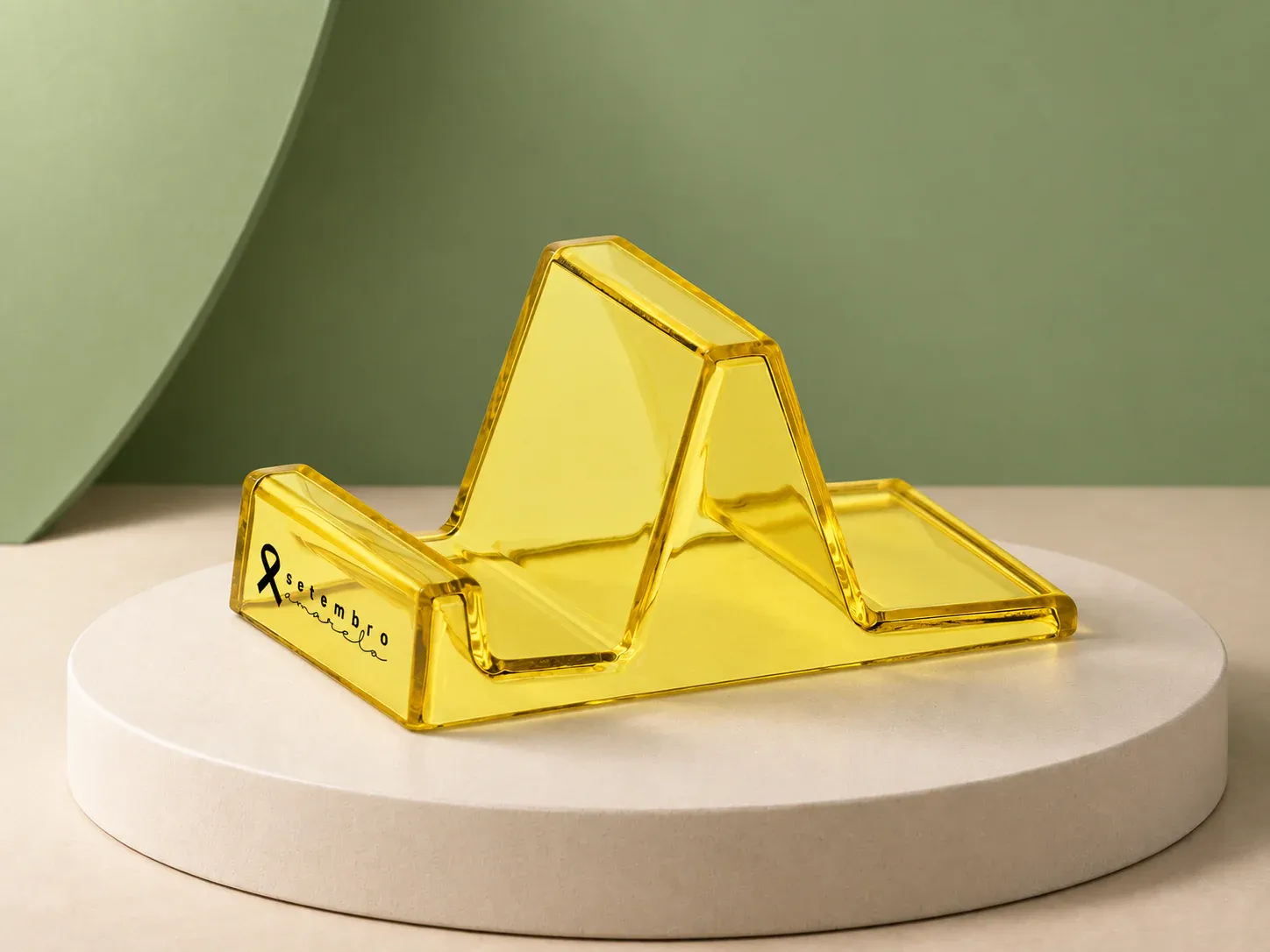 Suporte de celular de acrílico Setembro Amarelo, na cor amarelo, com a arte da campanha e sem a sua marca: suporte de celular amarelo translúcido em formato de rampa, com laço e "setembro amarelo" impressos na lateral