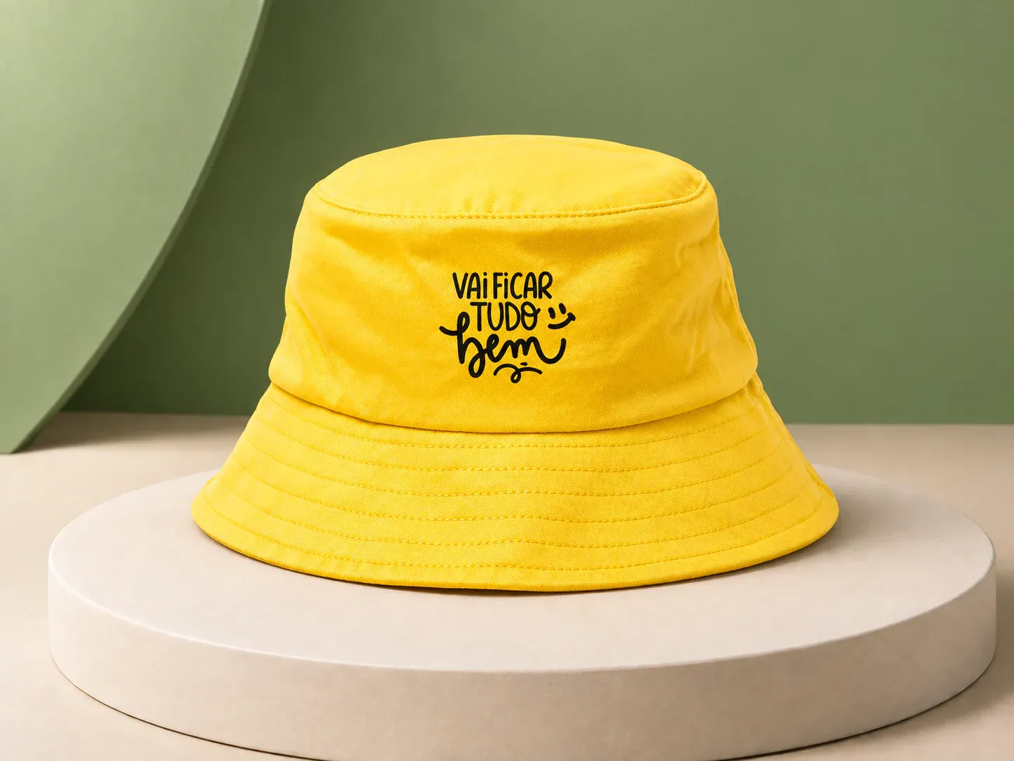 Chapéu bucket Setembro Amarelo, na cor amarelo, com a arte da campanha e sem a sua marca: chapéu bucket amarelo com aba pespontada e a frase "Vai ficar tudo bem" em preto na frente da copa