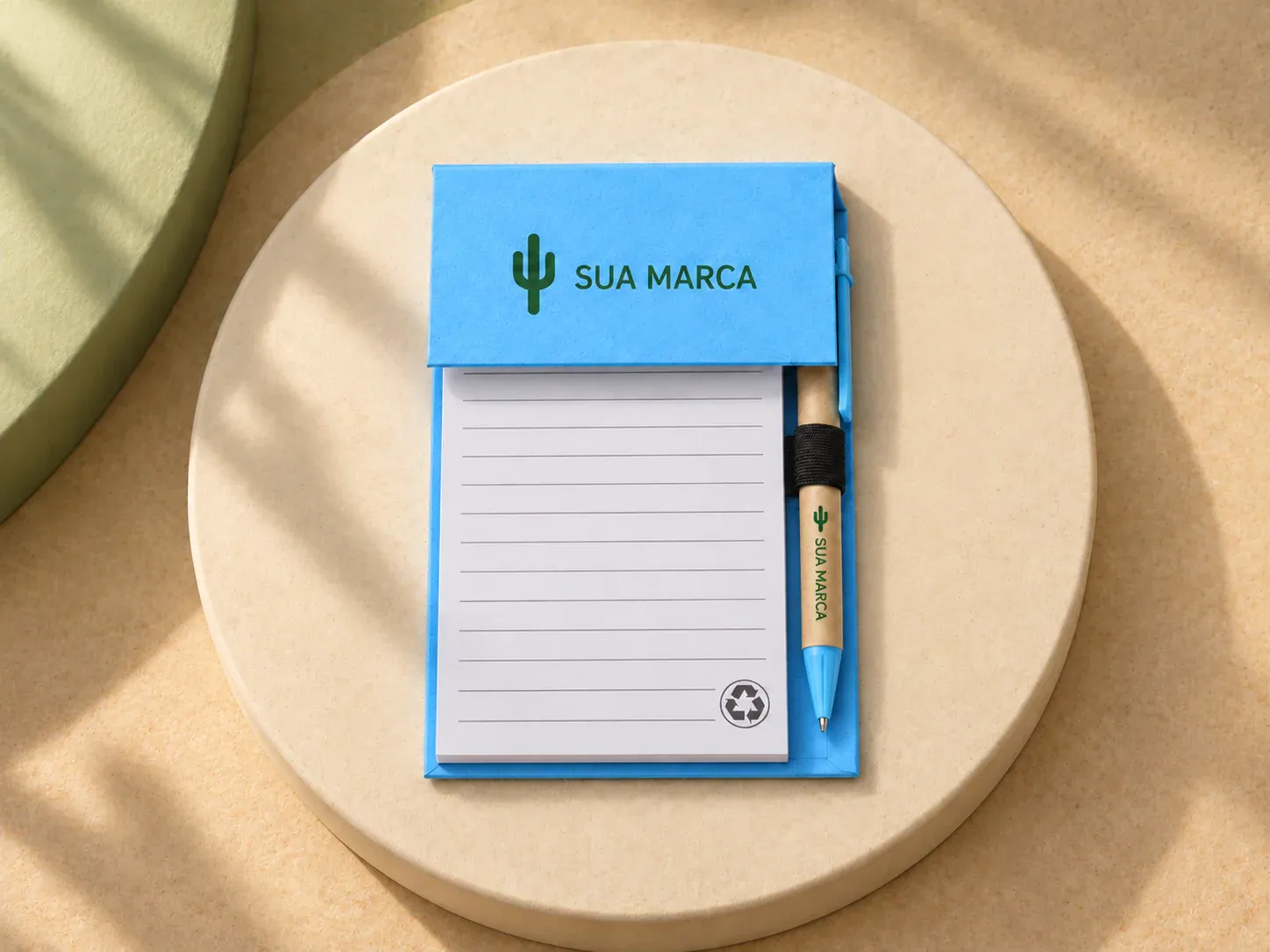 Bloco de anotações com autoadesivos e caneta, com exemplo de personalização colorida: um cacto e o texto “SUA MARCA” impressos em cor