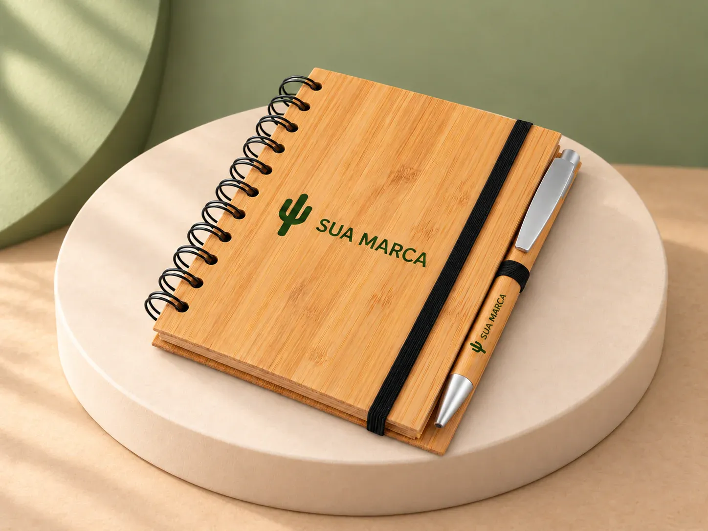 Caderno ecológico com caneta, com exemplo de personalização colorida: um cacto e o texto “SUA MARCA” impressos em cor